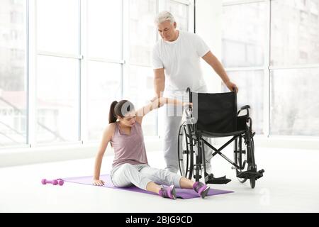 Junge behinderte Frau mit Senior Orthopäde in der Rehabilitationsklinik Stockfoto