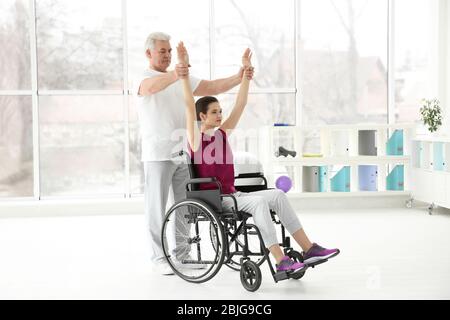 Junge behinderte Frau mit Senior Orthopäde in der Rehabilitationsklinik Stockfoto