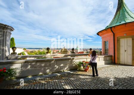 Eine Frau fotografiert das Prager Stadtbild einschließlich des Altstadtteils von einer Terrasse im Prager Schlosskomplex in Prag, Tschechien Stockfoto