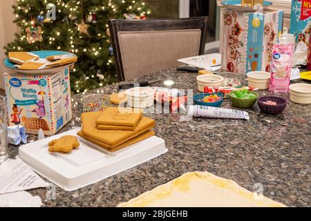 Abwechslungsreiche Lebkuchen Haus Zutaten sind auf einer Granit-Küche Theke mit einem beleuchteten Weihnachtsbaum hinter gelegt. Stockfoto