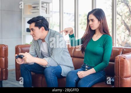 Porträt der Frau Gefühl beleidigt mit ihrem Freund, wenn er Videospiele spielen, während auf der Couch im Wohnzimmer sitzen. Paar Liebe Beziehung Stockfoto