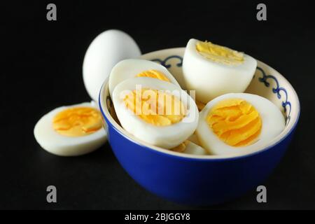 Schüssel mit Scheiben hart gekochte Eier auf schwarzem Hintergrund. Ernährungskonzept Stockfoto