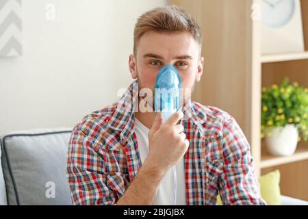 Junger Mann, der zu Hause Vernebler für Asthma und Atemwegserkrankungen verwendet Stockfoto