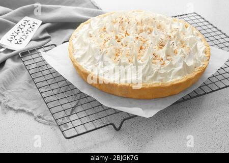 Gitter mit köstlicher Kokosnusscreme-Torte auf grauem Tisch Stockfoto