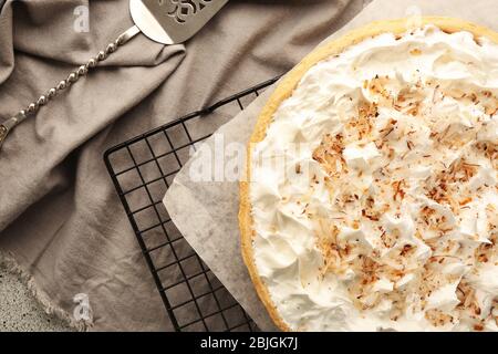 Gitter mit köstlicher Kokosnusscreme-Torte auf grauem Tisch Stockfoto