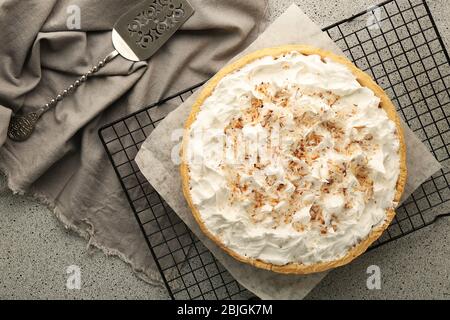 Gitter mit köstlicher Kokosnusscreme-Torte auf grauem Tisch Stockfoto