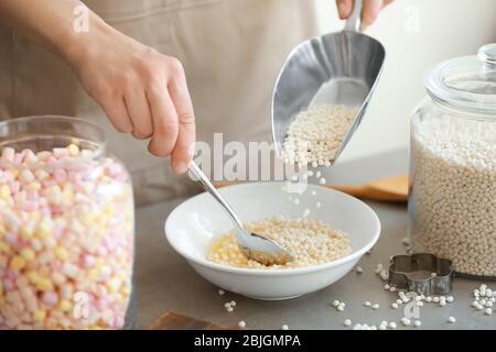 Frau Hinzufügen knusprige Reisbällchen in Schüssel auf dem Tisch Stockfoto