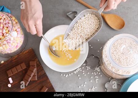 Frau Hinzufügen knusprige Reisbällchen in Keramik Schüssel auf dem Tisch Stockfoto