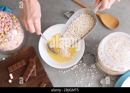 Frau Hinzufügen knusprige Reisbällchen in Keramik Schüssel auf dem Tisch Stockfoto