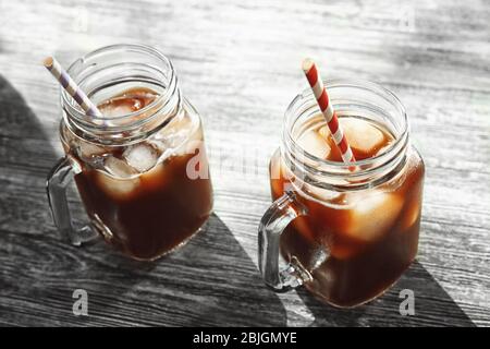Mason Gläser mit kaltem Kaffee und Strohhalme auf Holztisch Stockfoto