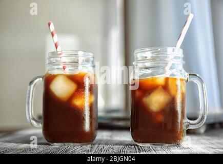 Mason Gläser mit kaltem Kaffee und Strohhalme auf Holztisch Stockfoto