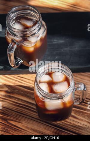 Mason Gläser mit kaltem Kaffee und Eis auf Holztisch Stockfoto