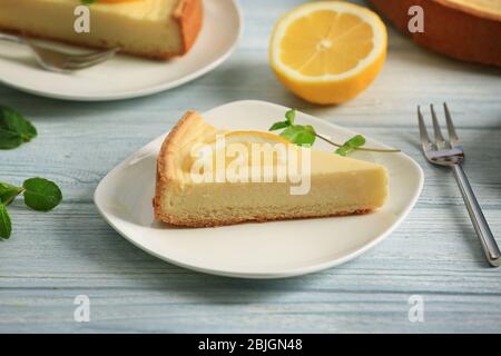 Teller mit köstlichem Käsekuchen und Zitronenscheibe auf Holztisch Stockfoto