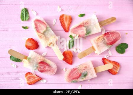 Hausgemachte Eis Pops mit Blumen und Erdbeere auf Farbe Holzhintergrund Stockfoto