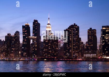 Blick in die Abenddämmerung auf die Skyline von Manhattan mit dem berühmten Empire State Building vom East River in New York City aus gesehen Stockfoto