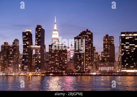 Blick in die Abenddämmerung auf die Skyline von Manhattan mit dem berühmten Empire State Building vom East River in New York City aus gesehen Stockfoto