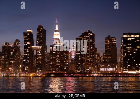 Blick in die Abenddämmerung auf die Skyline von Manhattan mit dem berühmten Empire State Building vom East River in New York City aus gesehen Stockfoto