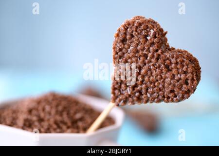 Herzförmige knusprige Dessert in Tasse auf blauem Hintergrund Stockfoto