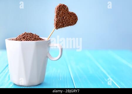 Herzförmiges knuspriges Dessert in Tasse auf Holztisch Stockfoto
