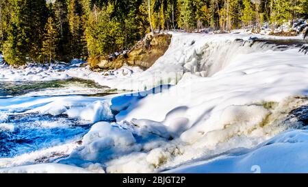 Das Wasser des Murtle River stürzt über den Rand der teilweise gefrorenen Dawson Falls in den Cariboo Mountains des Wells Grey Provincial Park Stockfoto