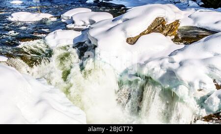 Das Wasser des Murtle River stürzt über den Rand der teilweise gefrorenen Mushbowl Falls in den Cariboo Mountains des Wells Grey Provincial Park Stockfoto