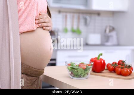 Junge schwangere Mädchen stehen in der Nähe Tisch mit Frühstück in der Küche Stockfoto