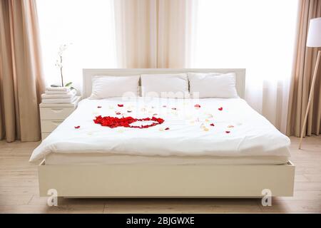 Rosenblätter auf dem Bett im Hotelzimmer Stockfoto