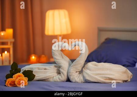 Zwei Schwäne aus Handtüchern auf dem Bett im Hotelzimmer. Honeymoon-Konzept Stockfoto