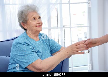 Junge Dame, die älteren Frauen ein Glas Wasser gibt. Konzept der Pflege Stockfoto