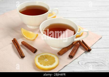 Zwei Tassen mit aromatischem heißen Zimttee und Zitrone auf Holztisch Stockfoto