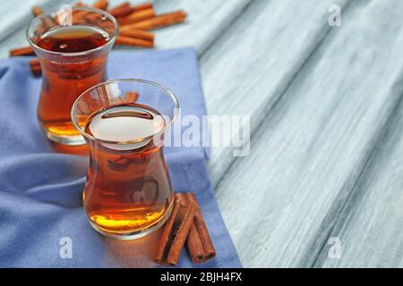 Zwei Glasbecher mit aromatischem heißen Zimttee auf Holztisch Stockfoto