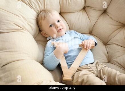 Niedlicher kleiner Junge mit Buchstabe V im Sessel Stockfoto
