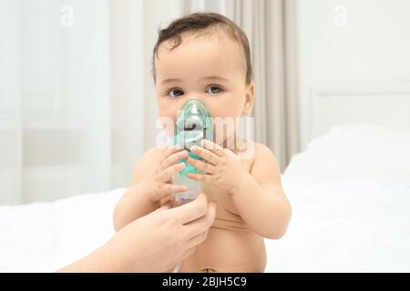 Mutter mit Vernebler für niedliche kleine Baby sitzen auf dem Bett zu Hause. Konzept der Gesundheitsfürsorge Stockfoto