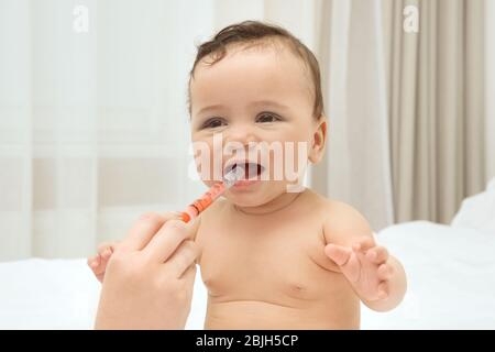 Mutter verwendet spezielle Spritze, um ihr Kind zu Hause Medikamente zu geben. Konzept der Gesundheitsfürsorge Stockfoto