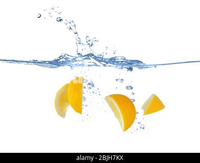 Frische Zitronenscheiben, die auf weißem Hintergrund in Wasser spritzen Stockfoto