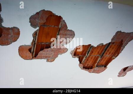 Bauloch in einem Riss an der weißen Wand und roten Ziegel und Beton Stockfoto