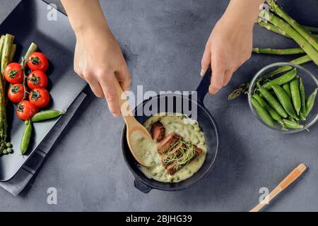 Mann, der Sauce zu geschnittenem Steak in der Pfanne hinzufügt Stockfoto