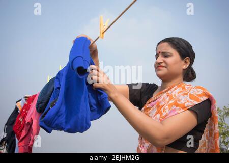 indische Frau trocknet Kleidung auf Wäscheleine Stockfoto