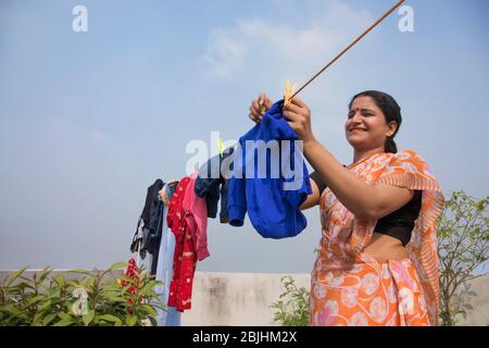 indische Frau trocknet Kleidung auf Wäscheleine Stockfoto