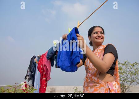 indische Frau trocknet Kleidung auf Wäscheleine Stockfoto