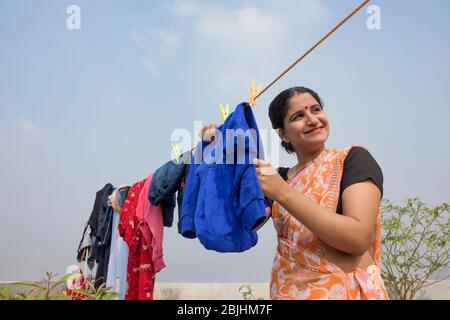 indische Frau trocknet Kleidung auf Wäscheleine Stockfoto