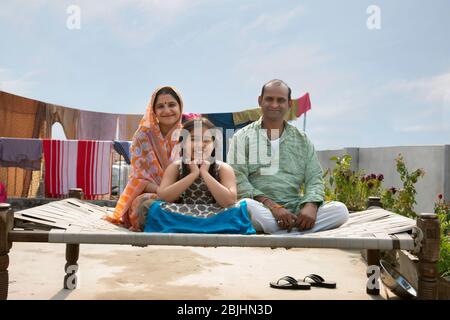 indische Eltern und Tochter sitzen auf einem Lagerbett Stockfoto