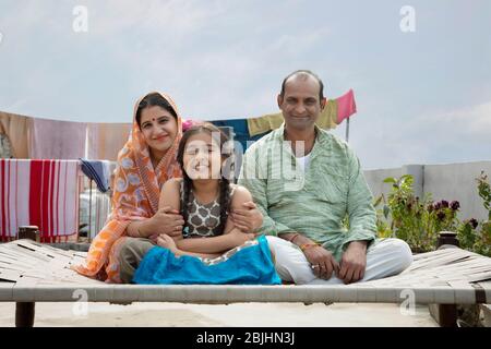 indische Eltern und Tochter sitzen auf einem Lagerbett Stockfoto