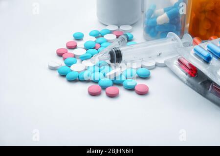 Konzept der Gesundheitsfürsorge. Zusammensetzung mit Pillen und Spritze auf weißem Hintergrund Stockfoto