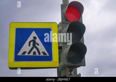 Ampel mit einem brennenden roten Signal. Ampel mit brennendem roten Licht auf einem Hintergrund mit bewölktem Himmel. Stockfoto