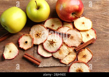 Komposition mit leckeren Apfelchips und Zimt auf Holztisch Stockfoto