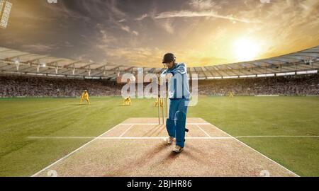 Der junge Sportler schlägt den Ball beim Schlagstock auf dem Cricket-Feld Stockfoto