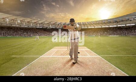 Der junge Sportler schlägt den Ball beim Schlagstock auf dem Cricket-Feld Stockfoto