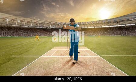 Der junge Sportler schlägt den Ball beim Schlagstock auf dem Cricket-Feld Stockfoto