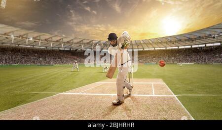 Der junge Sportler schlägt den Ball beim Schlagstock auf dem Cricket-Feld Stockfoto